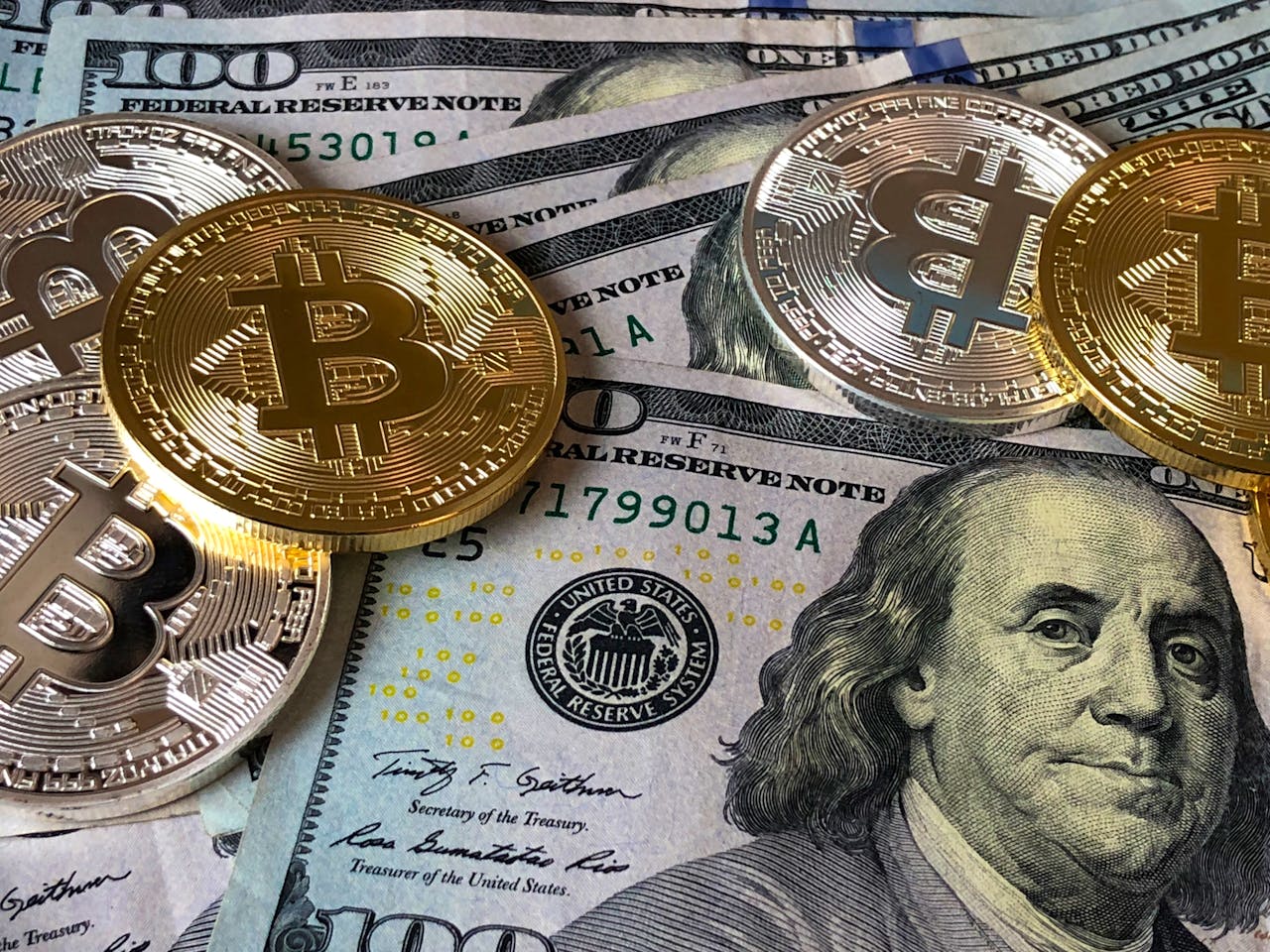 menu-11 A close-up photo depicting Bitcoin coins on top of US dollar bills, symbolizing finance and cryptocurrency.