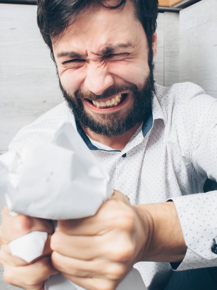 Mastering the First Impression: Your intriguing post title goes here A stressed bearded man crumples paper in frustration indoors, showing intense emotion.