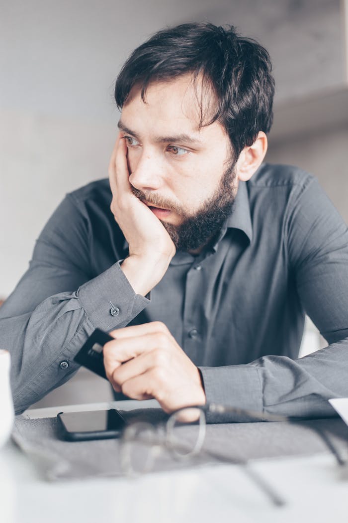 menu-03 A worried man in a gray shirt holds a credit card, symbolizing online fraud or financial stress.